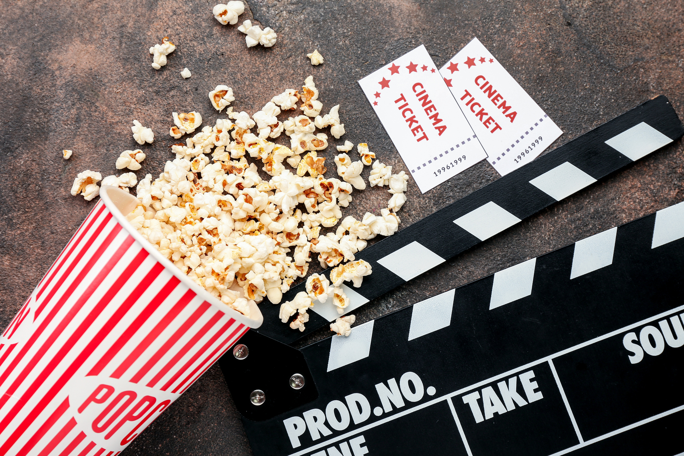 Popcorn, Cinema Tickets and Movie Clapper on Grunge Background